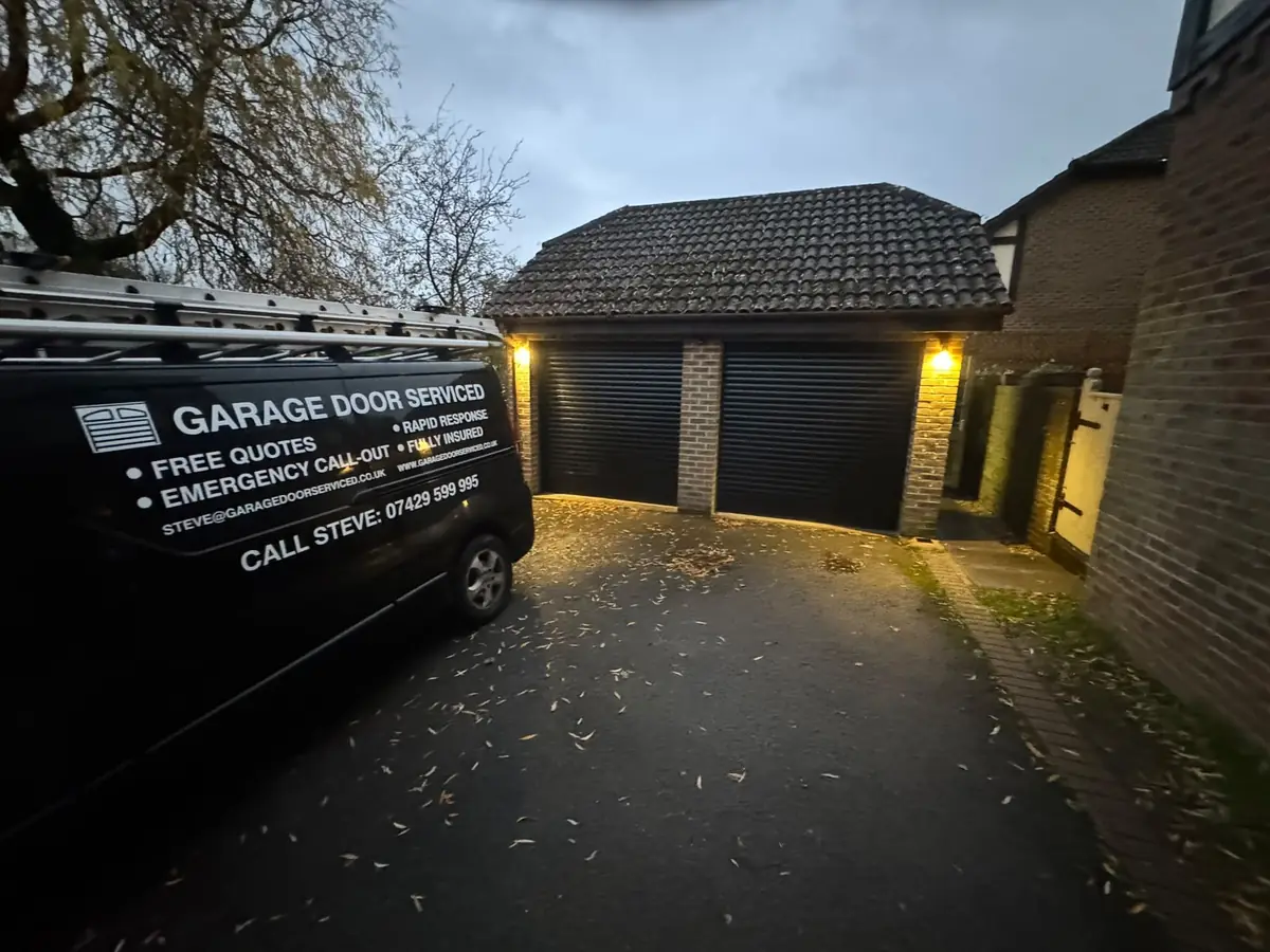 Garage Door Serviced van on the drive of a double garage with two black roller doors