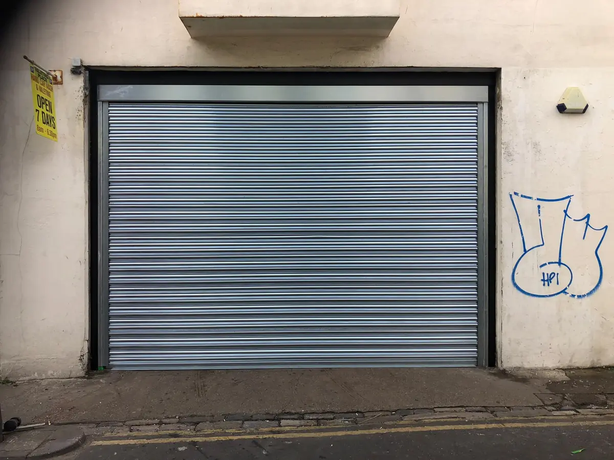 Wide galvanised roller shutter on a rendered commercial building
