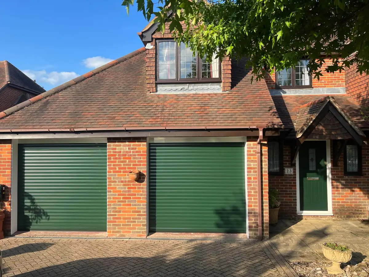 Pair of green roller garage doors on a brick house