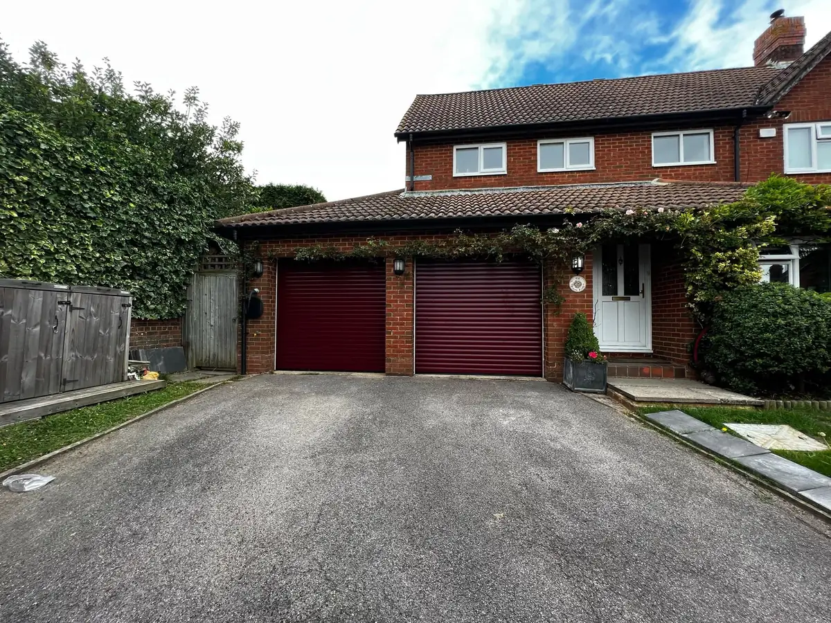 Pair of burgundy roller garage doors on a detached brick house