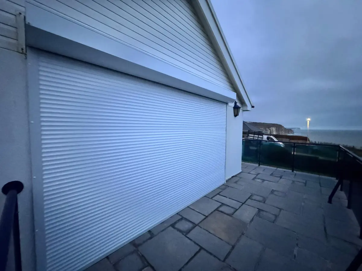 Wide white roller door on a house with a terrace overlooking the sea