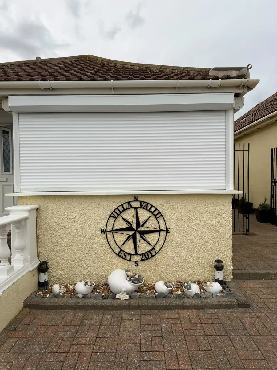 White roller shutter fitted over the front window of a bungalow