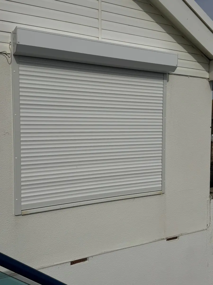 White roller shutter closed over a window on a rendered wall