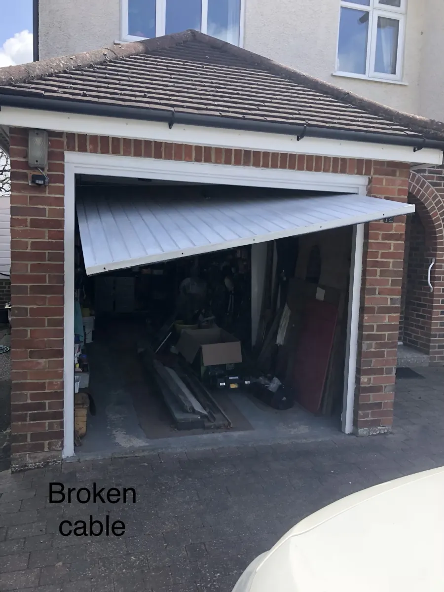 Up and over garage door hanging open at an angle after a cable snapped