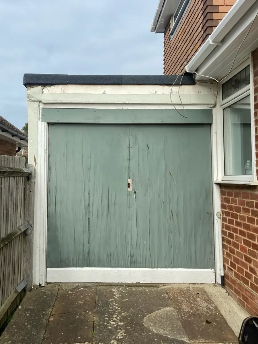 Weathered green timber garage doors with peeling paint